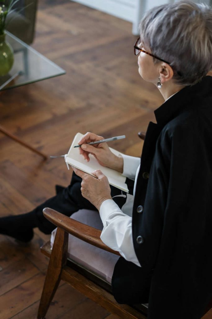 Woman in Black Blazer Holding White Notebook