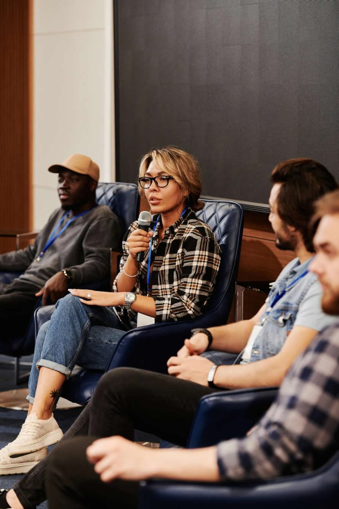 A Woman in Plaid Shirt Speaking over a Microphone